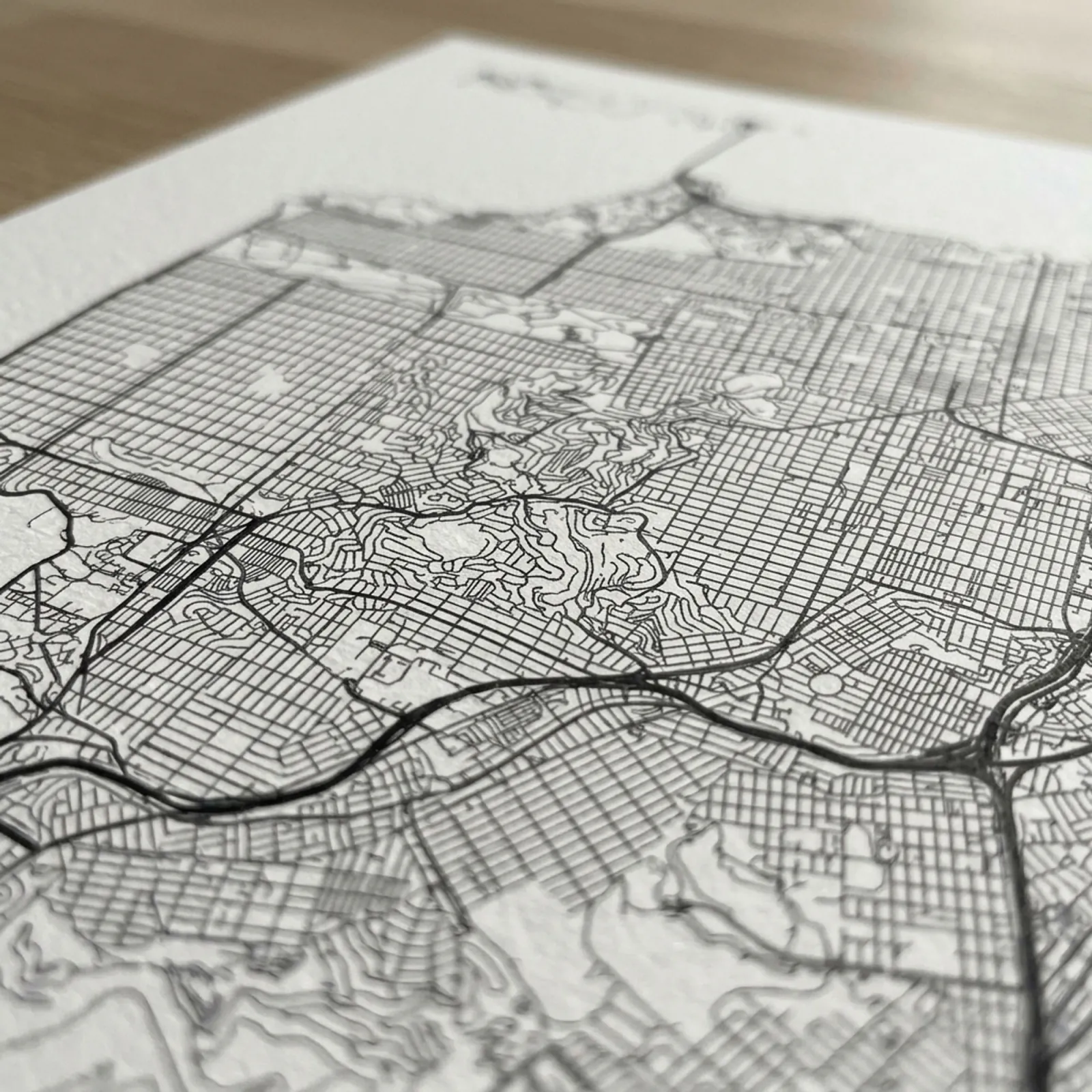 Close-up of a printed city map poster, ink lines raking across matte paper